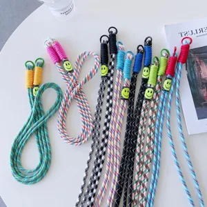 Colorful braided phone lanyard with smiley face charm, double buckle crossbody strap design.