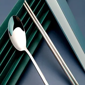 Détail de cuillère et baguettes en acier inoxydable avec une texture métallique polie.
