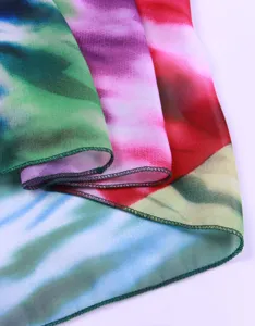 Nahaufnahme von buntem Batik-Chiffonstoff mit feiner grüner Kantenverarbeitung.