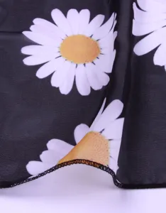 Detailansicht des schwarzen Chiffon Strandtuchs mit elegantem weißem Gänseblümchenmuster.