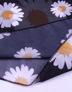 Nahaufnahme des schwarzen Chiffonstoffs mit weißem Gänseblümchen-Print und sauberer Saumnaht.
