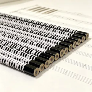 Piano keyboard pattern HB wooden pencils stationery detail shot on musical score background.