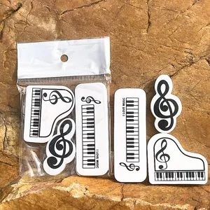 Vista detallada del conjunto de gomas de borrar creativas de piano y notas musicales en blanco.