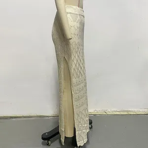 Detalle de falda larga de punto beige calado con abertura alta estilo playa.