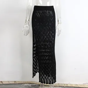 Falda maxi de punto calado negro con abertura alta, detalle de pareo de playa.