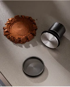 Detailed view of stainless steel coffee tamper base and coffee grounds cake with spiral pattern.