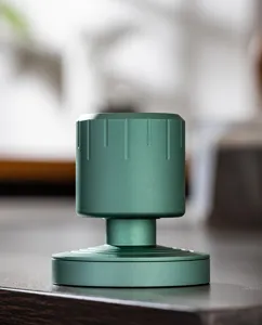 Green metal mini coffee tamper detail view, professional espresso constant pressure tool with base.