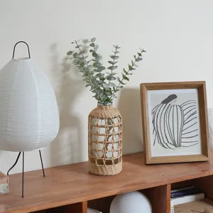 Housse de vase en verre tressée à la main décoration d'intérieur détail branches d'eucalyptus.