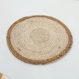Gros plan détaillé du set de table rond en paille naturelle au design bicolore élégant.
