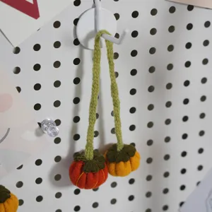 Close-up of cute handmade knitted pumpkin hanging ornaments with green textured straps for decor.
