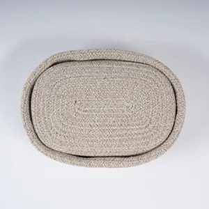 Woven cotton rope storage basket, oval organizer bin with lid, neutral home decor item.