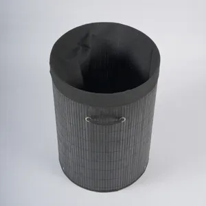 Detailed view of the black cylindrical bamboo laundry basket with fabric inner lining and handle.