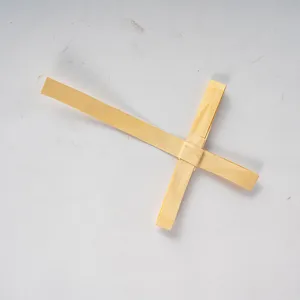 Primer plano de una cruz de palma tejida a mano en fibra natural para decoracion de pared.