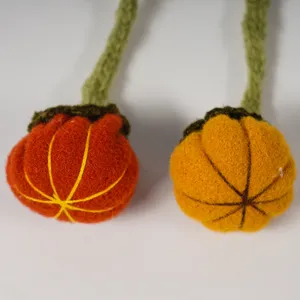 Close-up detail shot of handmade knitted pumpkin decorations with green stems, textured design.