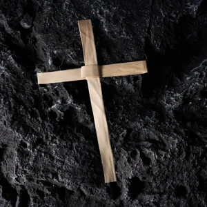 Detalle de cruz de hoja de palma tejida, decoración de pared rústica para iglesia.