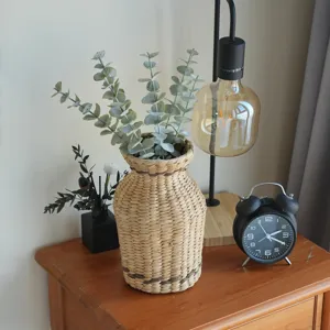 Nahaufnahme der geflochtenen Strohvase mit künstlichem Eukalyptus für Vintage Tischdeko.