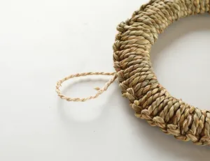 Primer plano detalle de salvamanteles trenzado en fibra natural con lazo para colgar.