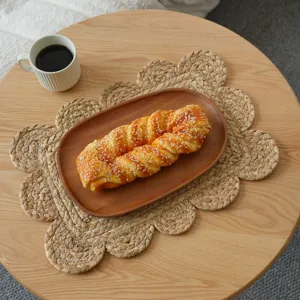Gros plan du set de table en paille tressé à la main avec un design floral délicat.