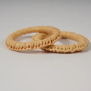 Handmade woven straw napkin ring detail shot, natural rustic tabletop decor accessory.