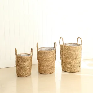 Detailed shot of three natural woven seagrass planters baskets with handles and inner lining.
