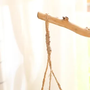 Détail de panier suspendu tissé en paille naturelle fait main avec branche de bois rustique.
