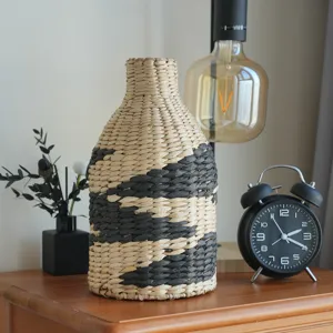 Vue détaillée du vase en paille tressée avec motif noir, ornement de décoration rustique fait main.