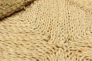 Close-up detail of natural corn leaf woven floor mat, showing tight straw texture and craft.
