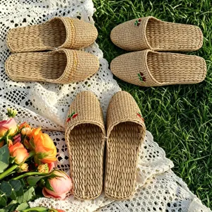Closeup of handmade woven straw slippers on lace fabric, showing breathable indoor texture.