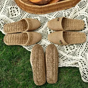Detail shot of handmade woven straw slippers displayed on lace mat and grass for natural style.