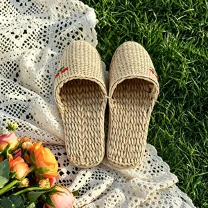 Handmade woven grass slippers detail shot showing intricate straw texture and floral embroidery.
