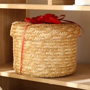 Round straw woven storage basket with lid and red ribbon bow, perfect for desktop and gift packaging.