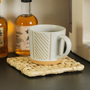 Handcrafted woven straw trivet and minimalist ceramic mug detail shot for kitchen and home decor use.