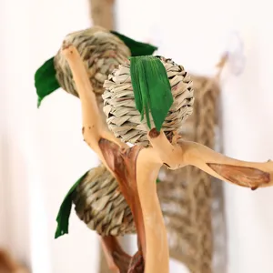 Natural woven grass pet chew ball toy with wooden branch stand, perfect for hamsters and rabbits.