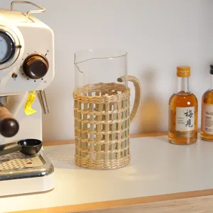 Handmade woven glass jug with natural rattan sleeve, minimalist home decor tabletop detail shot.