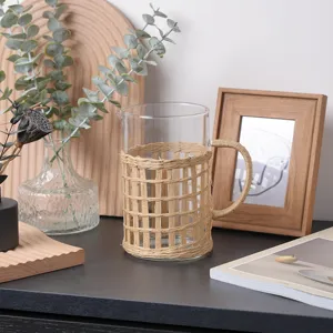 Detail view of a clear glass pitcher featuring a natural hand-woven rattan sleeve and handle.