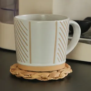 Handmade ceramic coffee mug with striped texture resting on a natural woven coaster.