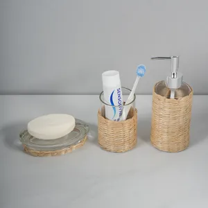 Detail view of woven rattan bathroom accessory set, natural straw and clear glass design.