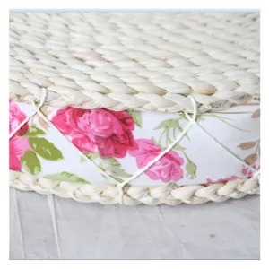 Handcrafted straw woven round cushion with pink floral fabric band and neat white rope binding.