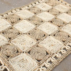 Detailed view of handcrafted natural seagrass woven floor mat with square textured patterns.