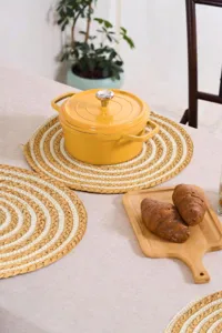 Close-up detail of handcrafted woven round placemat made of raffia and cotton rope for table.
