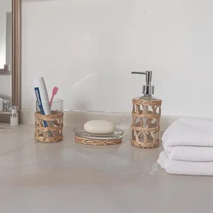 Vue de détail de l'ensemble distributeur de savon et porte-brosse à dents en rotin et verre.