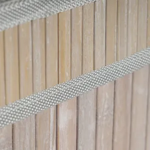 Gros plan détail de panier de rangement tissé en bambou naturel avec bordure textile grise.