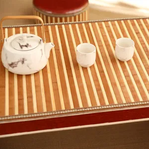 Detailed shot of a marble pattern ceramic teapot and two tea cups on a bamboo mat setup.