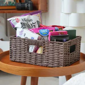 Detailansicht des braunen gewebten Aufbewahrungskorbs gefüllt mit Snacks auf Holztisch.