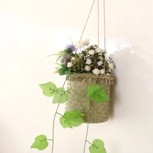 Handmade woven hanging flower basket with artificial flowers and green vines for home decor.