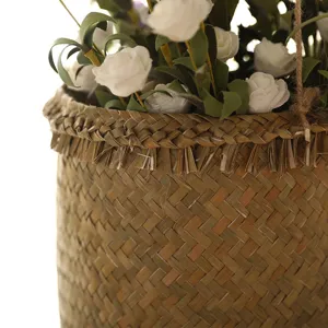 Close-up detail of hand-woven straw storage basket with artificial white flowers inside.
