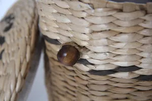 Detalle de cesta de almacenamiento tejida de paja con textura natural y cierre de botón de madera.