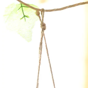 Close-up detail of hand-woven natural hemp rope hanging strap and green leaf decor for basket.