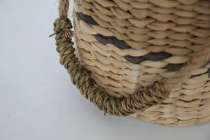 Vista detallada en primer plano del asa del cesto de paja tejido y su textura natural.