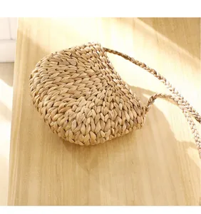 Handcrafted natural straw woven mini crossbody bag, casual summer beach shoulder bag style.